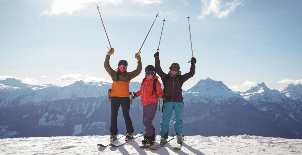 Grupo de personas caminando por un paisaje nevado con ropa de abrigo, gorros y gafas de sol. La imagen ilustra medidas de protección frente al frío y la radiación solar en actividades al aire libre.