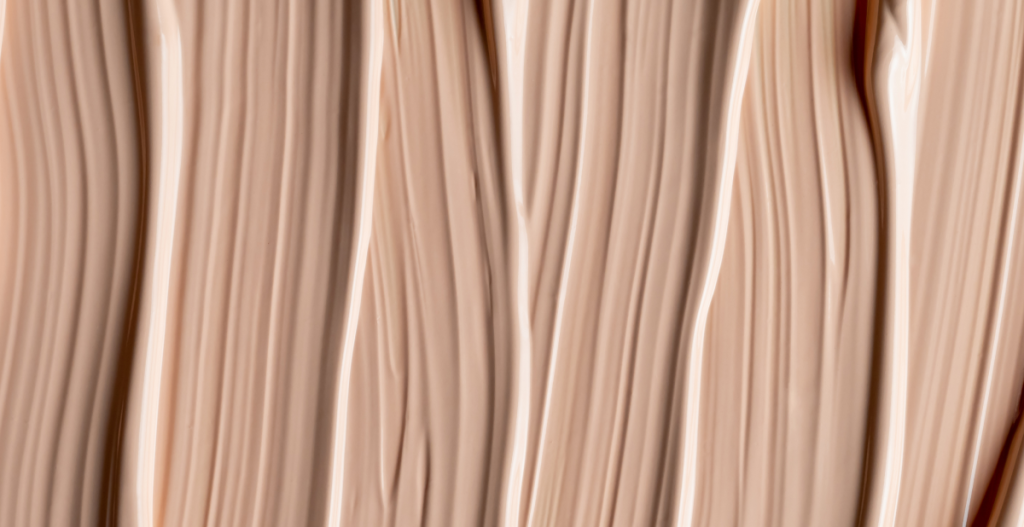 Textura de crema cosmética extendida en líneas suaves, representando productos diseñados para estimular la renovación y mejorar la barrera cutánea.