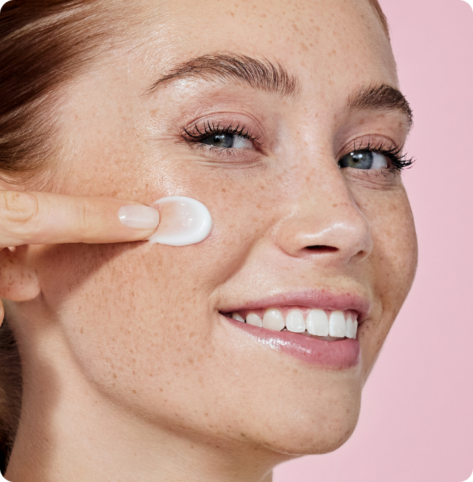 Primer plano de una mujer aplicando crema facial, ilustrando el uso de productos isdin equilibrados para mantener el pH saludable de la piel.