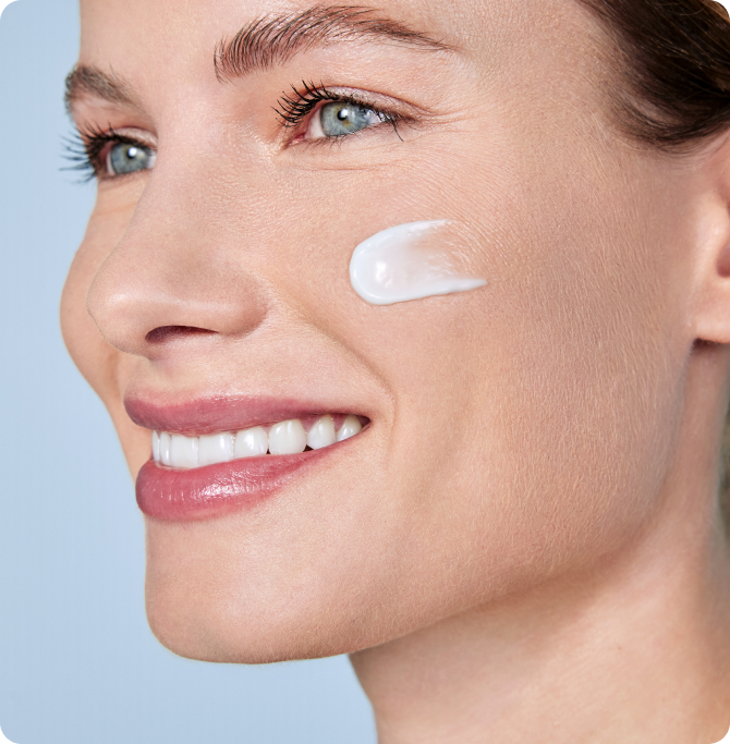 Mujer con una pequeña cantidad de crema ISDIN HYALURONIC MOISTURE en la mejilla, mostrando hidratación y cuidado de la barrera cutánea con pH balanceado.