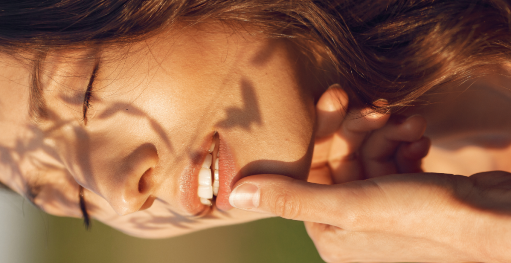 Mujer aplicando protector solar en el rostro con luz natural, destacando la importancia de la protección diaria frente a la radiación UV