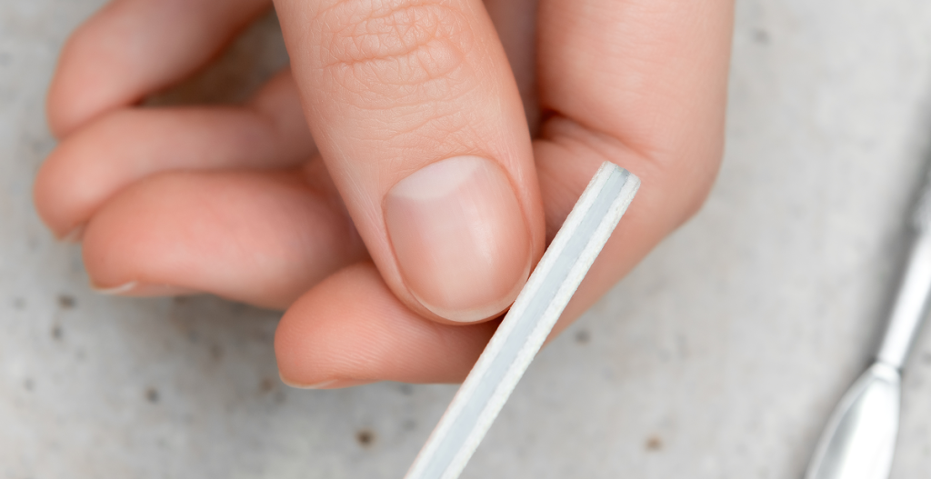 Persona limando sus uñas durante una rutina de manicura y cuidado