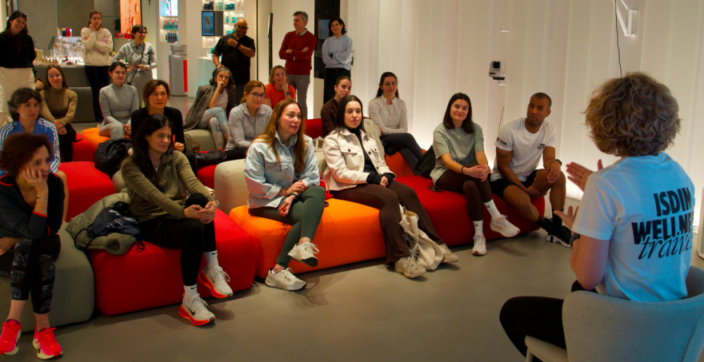 Grupo de personas escuchando una charla de bienestar en Casa ISDIN, sentadas en bancos de colores.