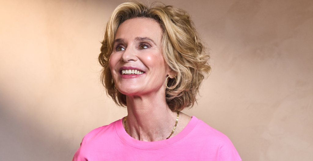 Retrato de la Dra. Marimer Pérez sonriendo, con camiseta rosa y fondo neutro cálido.