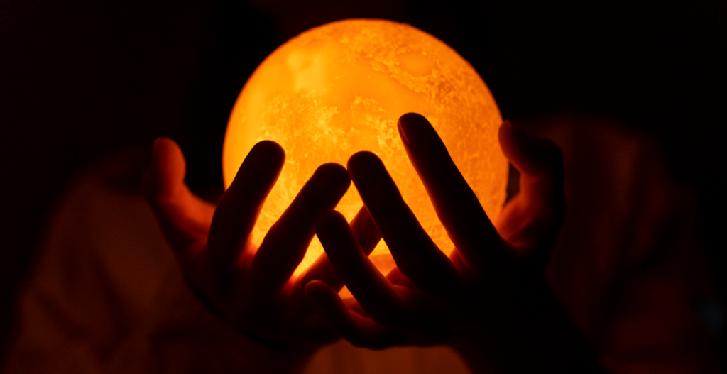 Manos sujetando una esfera luminosa que representa el Sol durante un eclipse solar