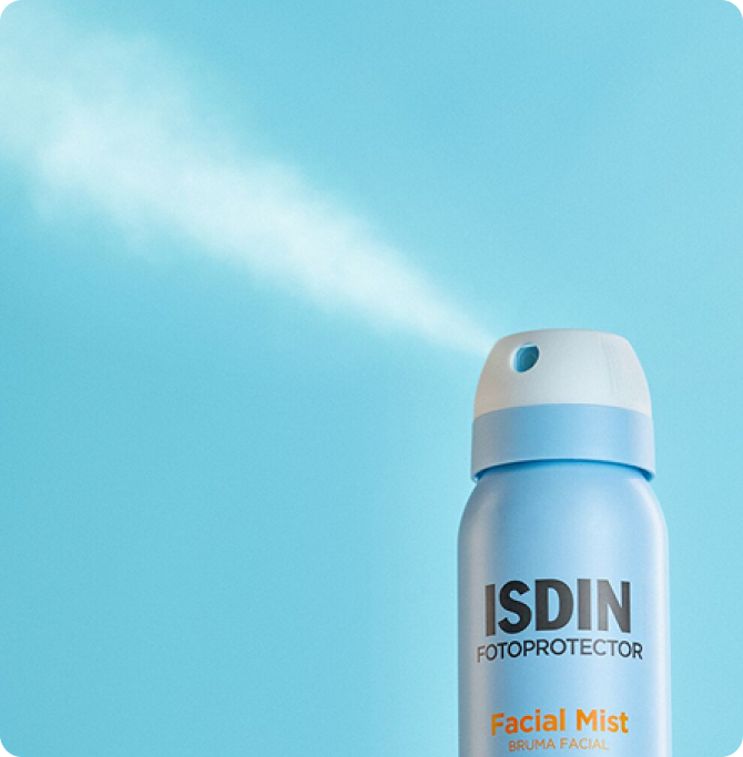 Bruma fina saliendo de un envase de ISDIN Facial Mist SPF 50 sobre fondo azul claro.