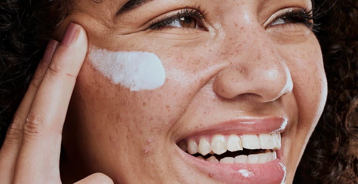 Woman with beautiful skin applying cream