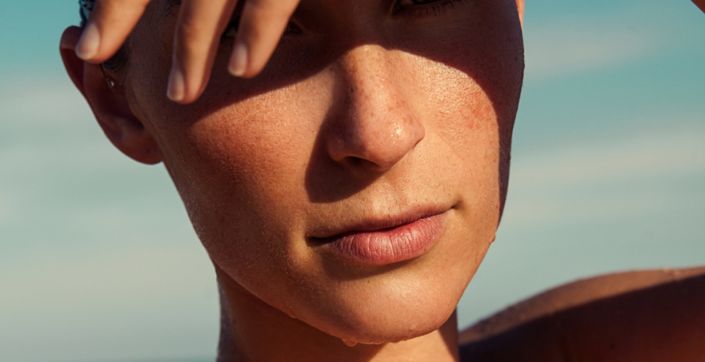 The near shot of a person who protects his face from the sun with his hand, showing the skin that had passed through the sun with visible freckles and texture.