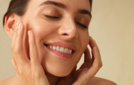 Close-up of a smiling person gently touching their face, soft blurred background, glowing skin. Represents new skincare habits and self-care for New Year resolutions.