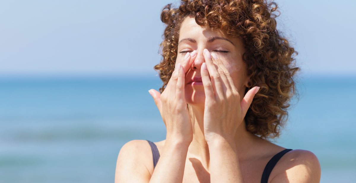 woman putting sunscreen on her face outside