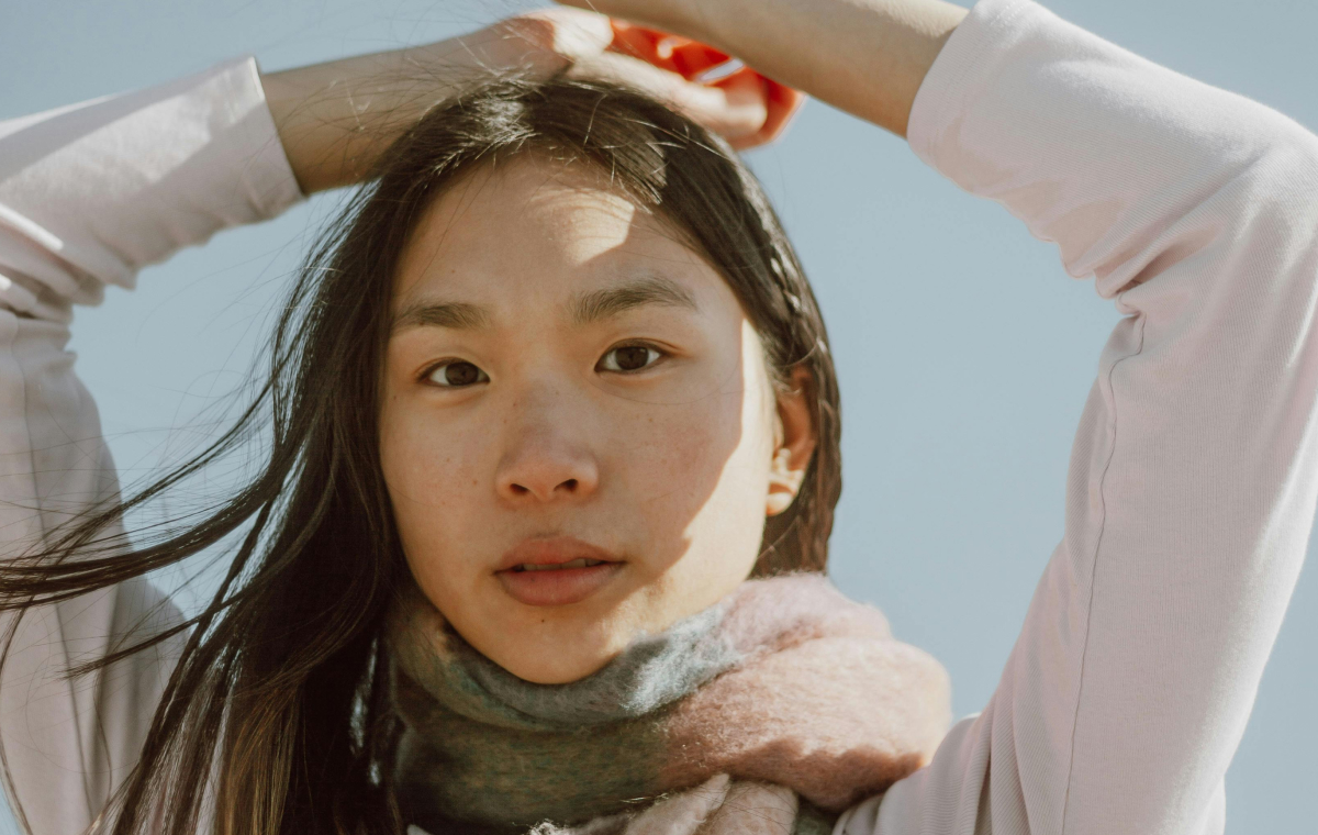 Woman outdoors in winter light wearing scarf, representing daily winter skincare habits to protect and nourish the skin