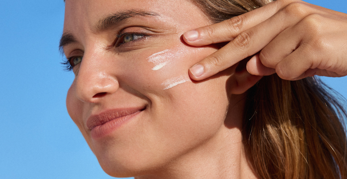 woman putting vitamin E sunscreen on her face woman putting vitamin E sunscreen on her face