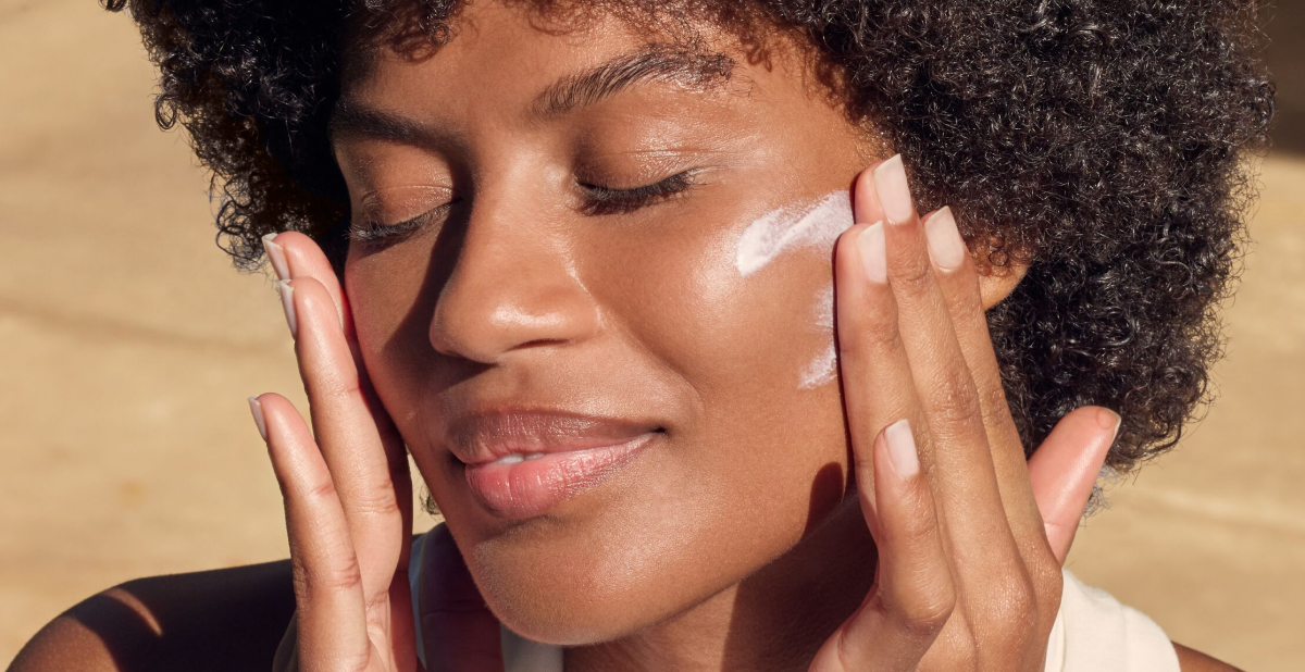 woman putting sunscreen on her face outside